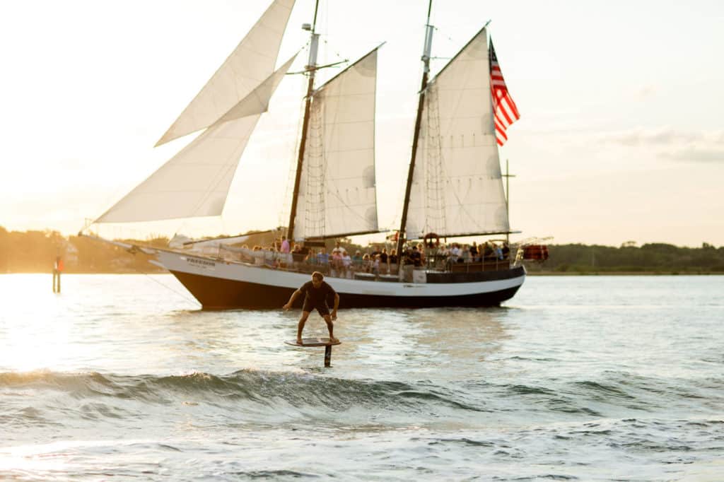 Brian Grubb foils alongside a sailboat