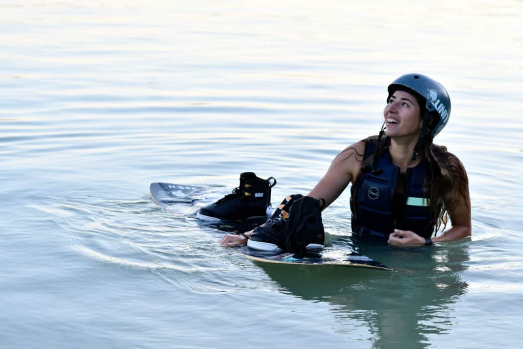 Wearing helmet standing in water next to board